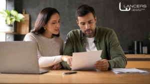 Casal analisando contrato de plano de saúde com carência em laptop e documentos na mesa da cozinha